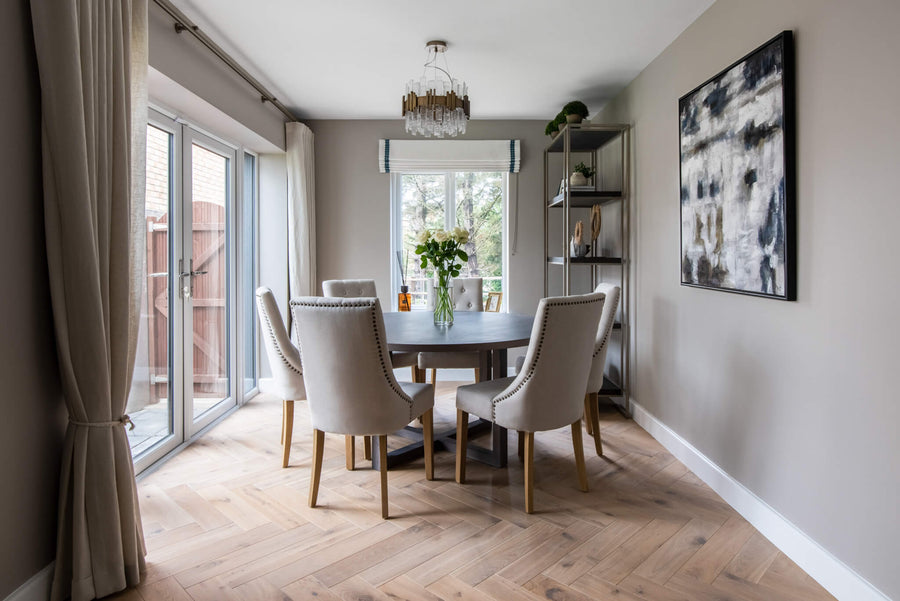 Dining room with a round table and upholstered chairs, sliding garden doors and an abstract canvas