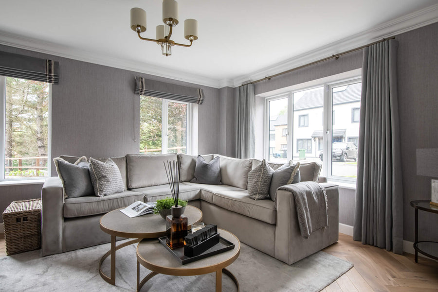 Living room with a large corner sofa, grey curtains and a brass chandelier