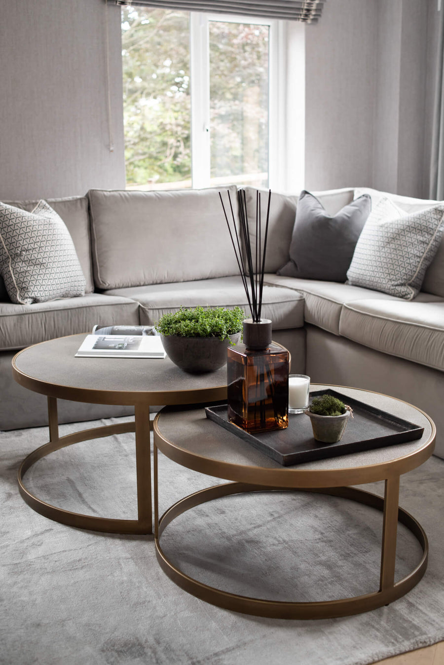 Corner sofa with nesting bronze coffee tables, a tray, diffuser and topiary