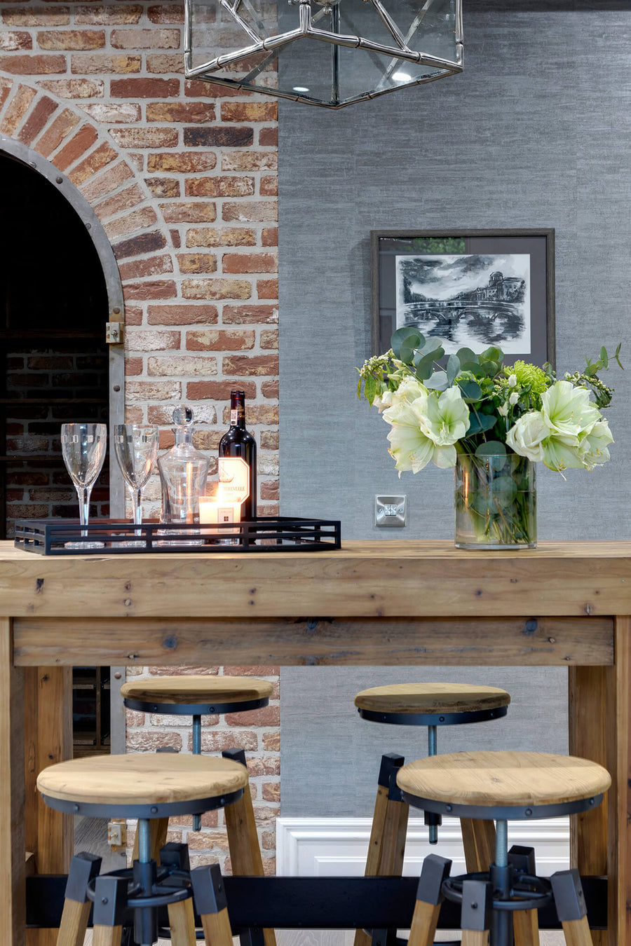Exposed brick arch with a timber bar counter, stools and glassware