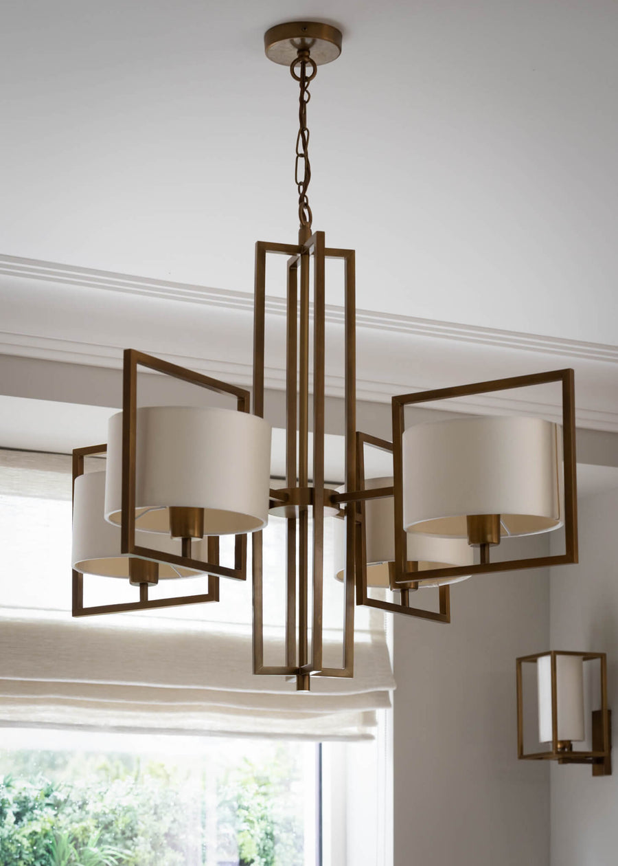 Brass and glass lantern chandelier hanging against a corniced ceiling