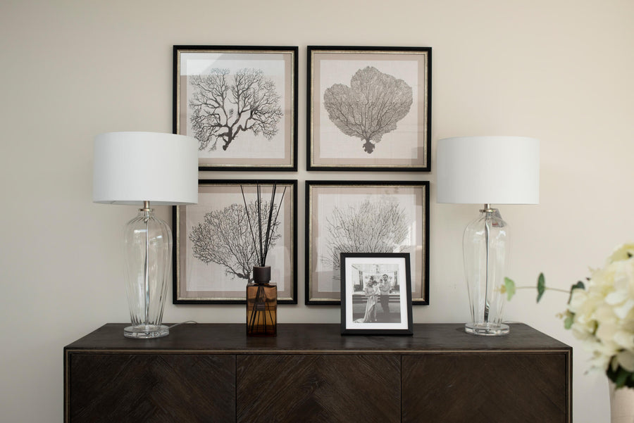 Dark timber sideboard with four framed botanical prints and a pair of glass table lamps