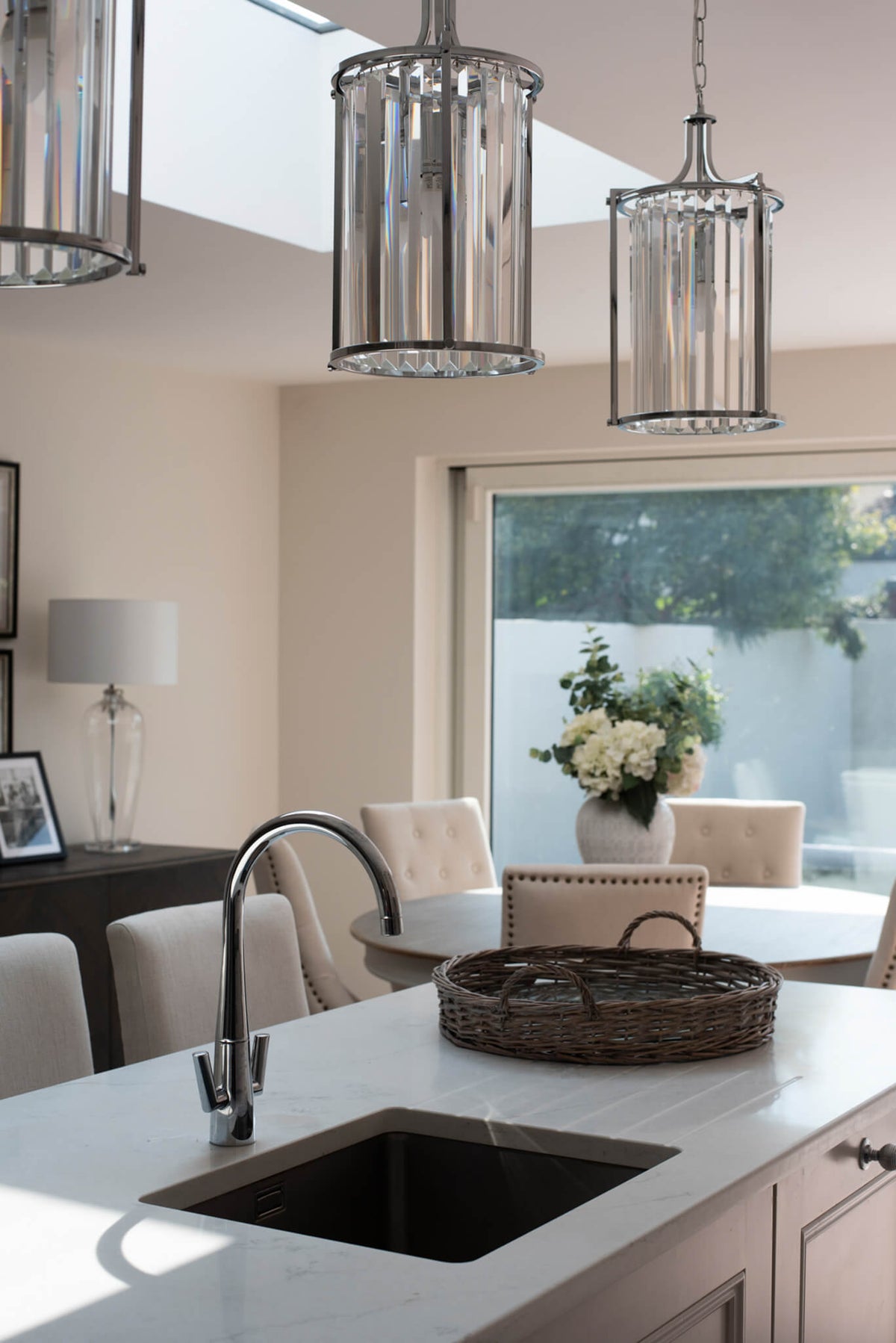 Kitchen island with an undermount sink and glass lantern pendants below a rooflight