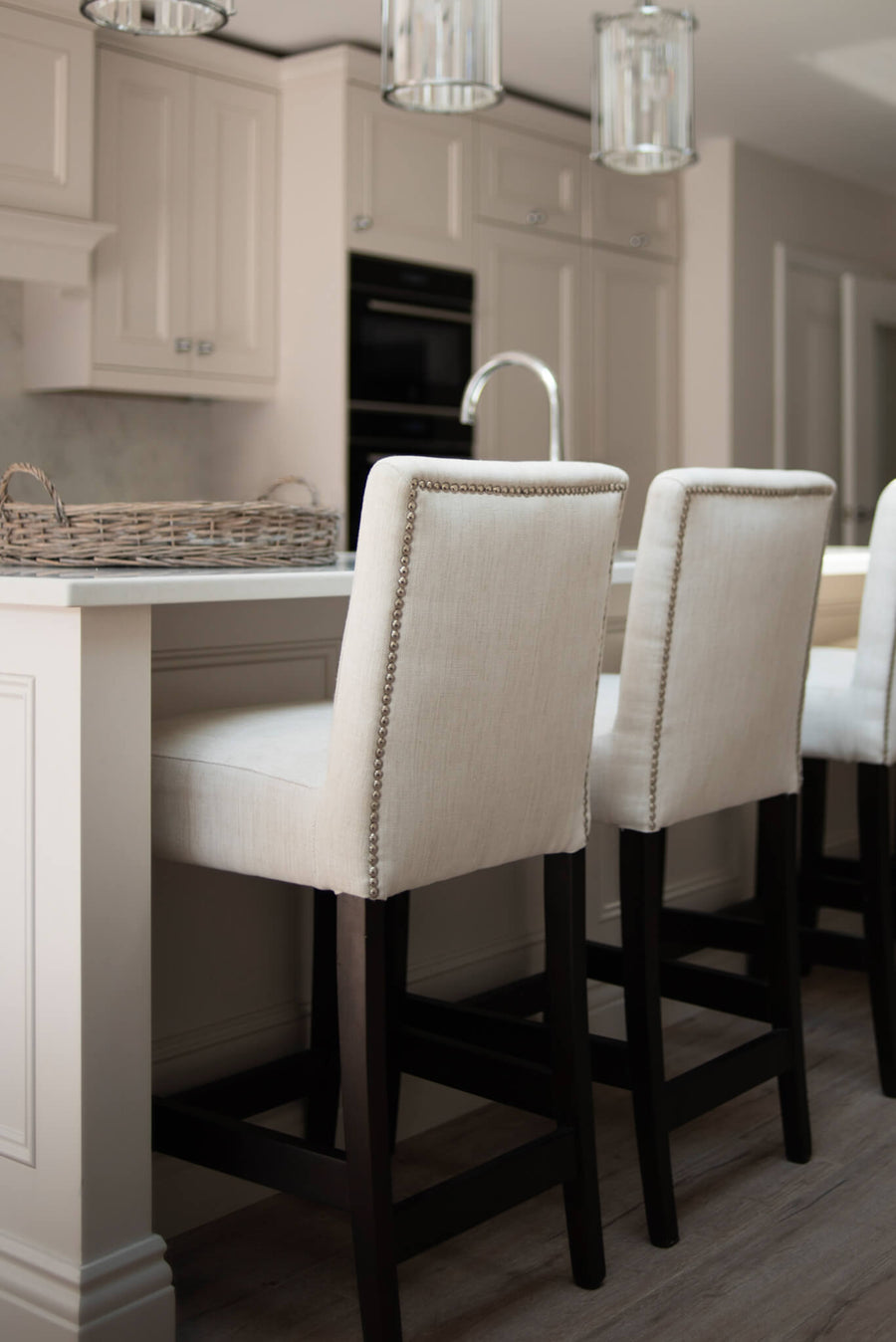 Cream kitchen with upholstered bar stools and faceted glass pendants