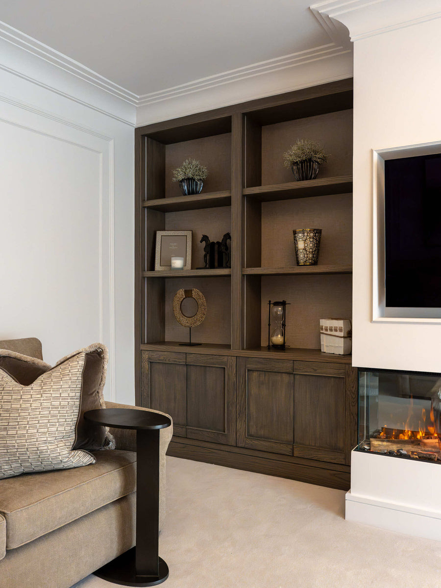 Bespoke dark timber joinery framing an inset fire, styled with ceramics and books