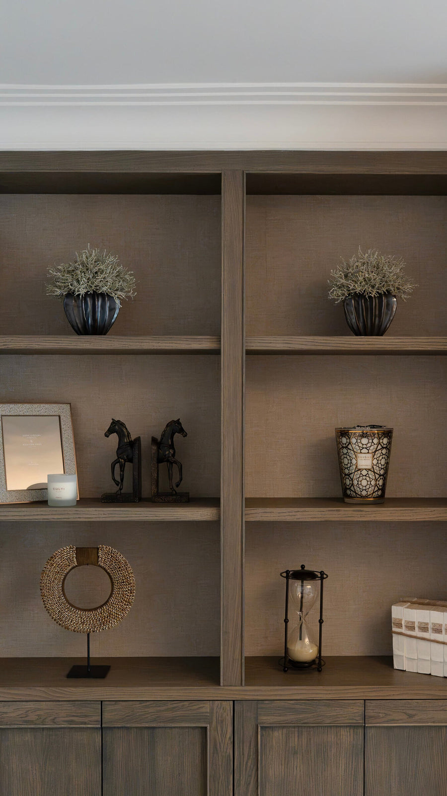 Open shelving in bespoke joinery styled with candles, ceramics and brass objects